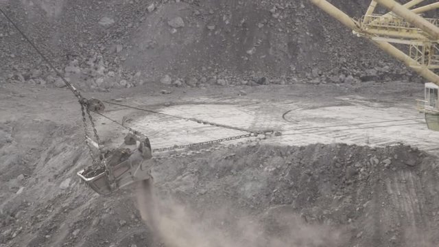 Dragline excavator walking on course throws dusty soil.