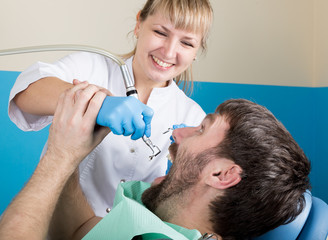 Doctor examines the oral cavity on tooth decay. Caries protection. Tooth decay treatment. Dentist working with dental polymerization lamp in oral cavity