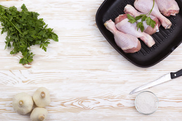 raw chicken drumstick in pan with salt, garlic, parsley