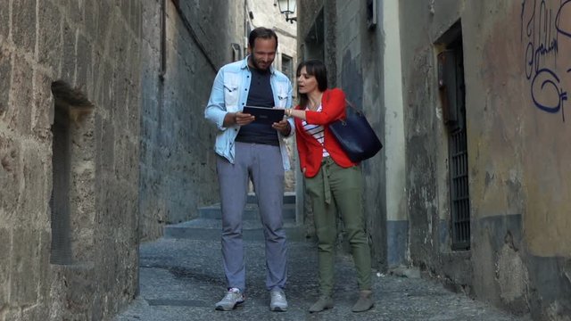 Young couple tourist checking map on tablet computer in city, super slow motion
