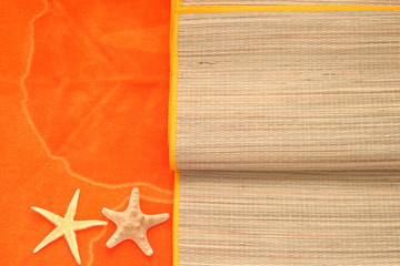 Fototapeta na wymiar sfondo marino, asciugamano da spiaggia arancione e stuoia di paglia con due stelle marine, vista dall'alto, luce solare, spazio testo