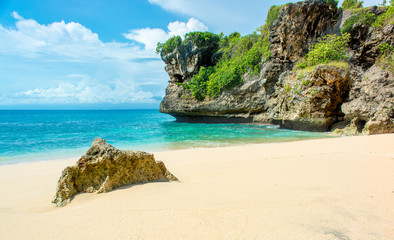 Deserted tropical Beach with cliff face  headland above the beautiful aqua colored water