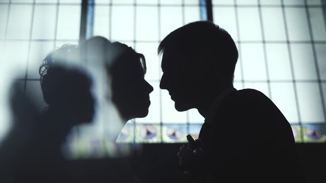 Silhouette of bride and groom in the interior against the window