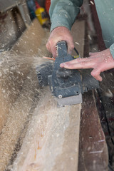 men planing a plank of wood with a electric plane