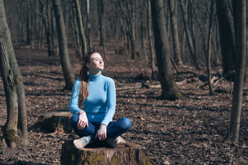 Naklejka na ściany i meble beautiful girl blonde sits in lotus pose in the middle of the forest in the spring