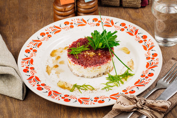 Russian herring salad on plate on wooden table