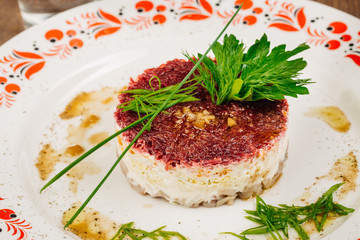 Russian herring salad on plate on wooden table