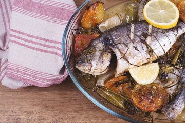 Baked fish with carrot,lemon and greenery.From above