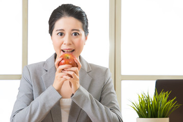 Young asian businesswoman eating healthy snack, apple