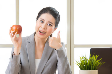 Young asian businesswoman holding apple and thumb up