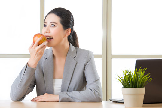 Young asian businesswoman eating healthy snack, apple - Powered by Adobe