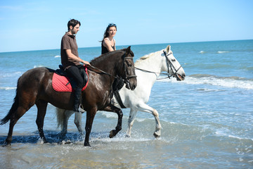 Fototapeta na wymiar happy young couple vacation riding horses on the beach in sunny summer day