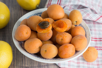 Fototapeta na wymiar Fresh organic apricots in glass bowl on wooden board