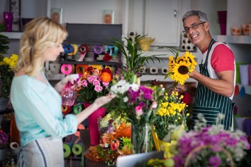 Fleuriste souriante pulvérisant de l& 39 eau sur les fleurs dans un magasin de fleurs