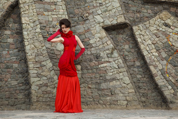Portrait of beautiful woman in red dress on stone wall background decoration