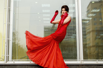 Beautiful woman in red dress on the background of a large window