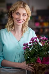 Happy female florist holding basket of flowers