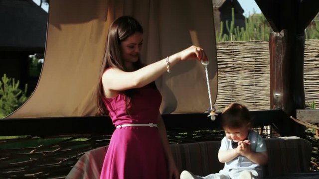 Mom plays with baby pacifier on nature