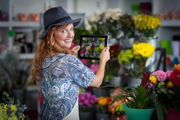 florist taking photograph of flowers from tablet 