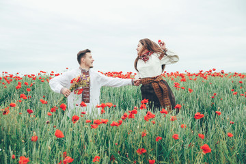 Lovely couple in the poppy field. Ukrainian traditional clothes