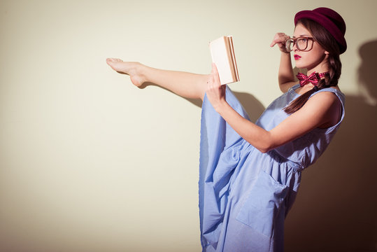 Portrait of pretty ballet dancer in red hat and glasses reading book