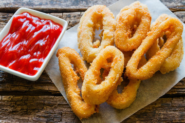squid rings with ketchup on a wooden background