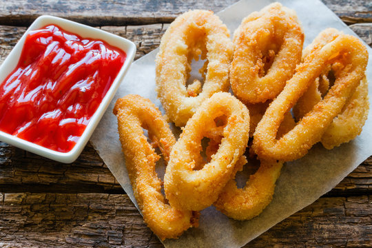 squid rings with ketchup on a wooden background
