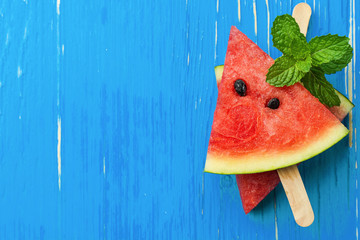 Watermelon slice popsicles on a blue rustic wood background, Pop
