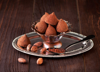 Chocolate truffles and cocoa beans on wooden background