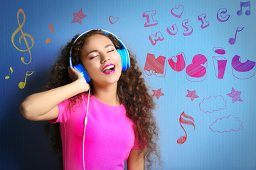 African American woman listening to music in headphones on blue background
