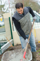 Builder mixing cement in a wheelbarrow