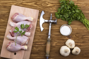 chicken drumstick on board with salt, parsley, garlic and ax