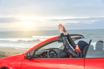 Woman on the beach in the cabriolet car.