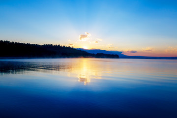 Fototapeta premium beautiful landscape with mountains and lake at dawn in golden, blue and purple tones. Slovakia Liptovska Mara, in region Liptov.