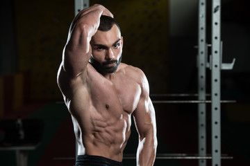 Fototapeta na wymiar Muscular Man Flexing Muscles In Gym