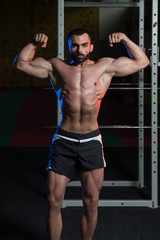 Fototapeta na wymiar Young Bodybuilder Flexing Muscles Double Biceps Pose