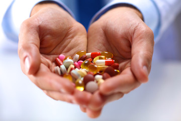 young doctor holding pills in his outstretched hand packaging