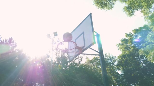 Young muscular man playing basketball in the park