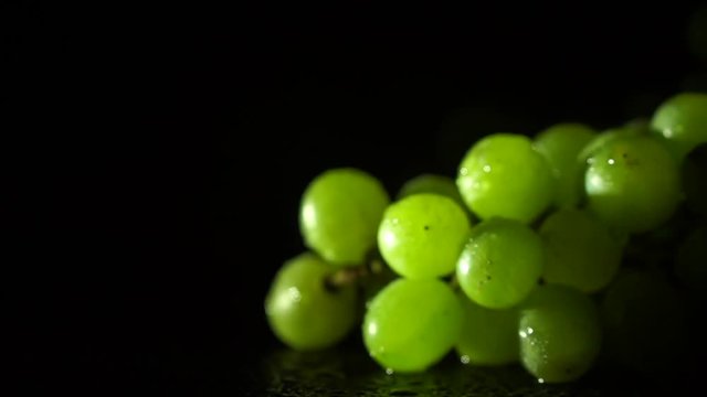 Sprig of green grapes on a platter on a black background
