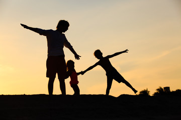 Obraz premium father with son and daughter silhouettes play at sunset