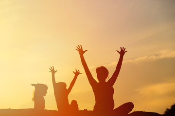 Silhouette of happy mother and kids at sunset