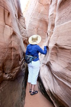 Woman squeezing through Zebra  slot canyon, Escalante Nanional Monument, Utah, USA. 