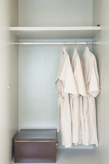 bathrobe hanging on rail in white wooden wardrobe