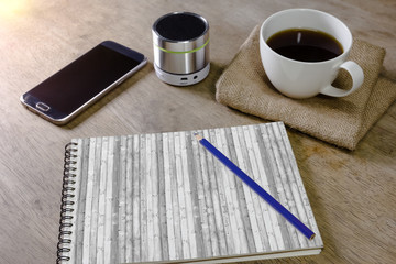 note book with coffee pencil speaker and smartphone on desktop