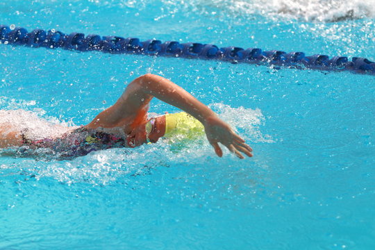 Woman with yellow swimming cap swim in the swimming pool