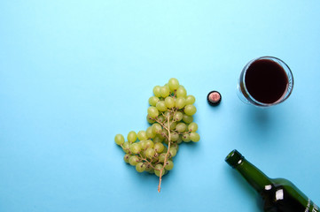 Glass, bottle of wine, green grapes on a blue background