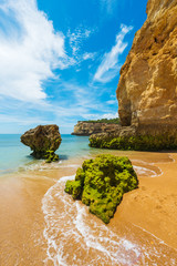Green stones on the beach Nova. Region Algarve. Portugal