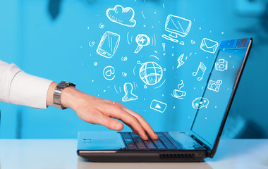 Hand writing on notebook computer with media icons