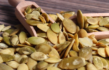 Pumpkin seeds with spoon on wooden background