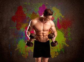 Fototapeta na wymiar Strong guy with colorful paint wall and weight